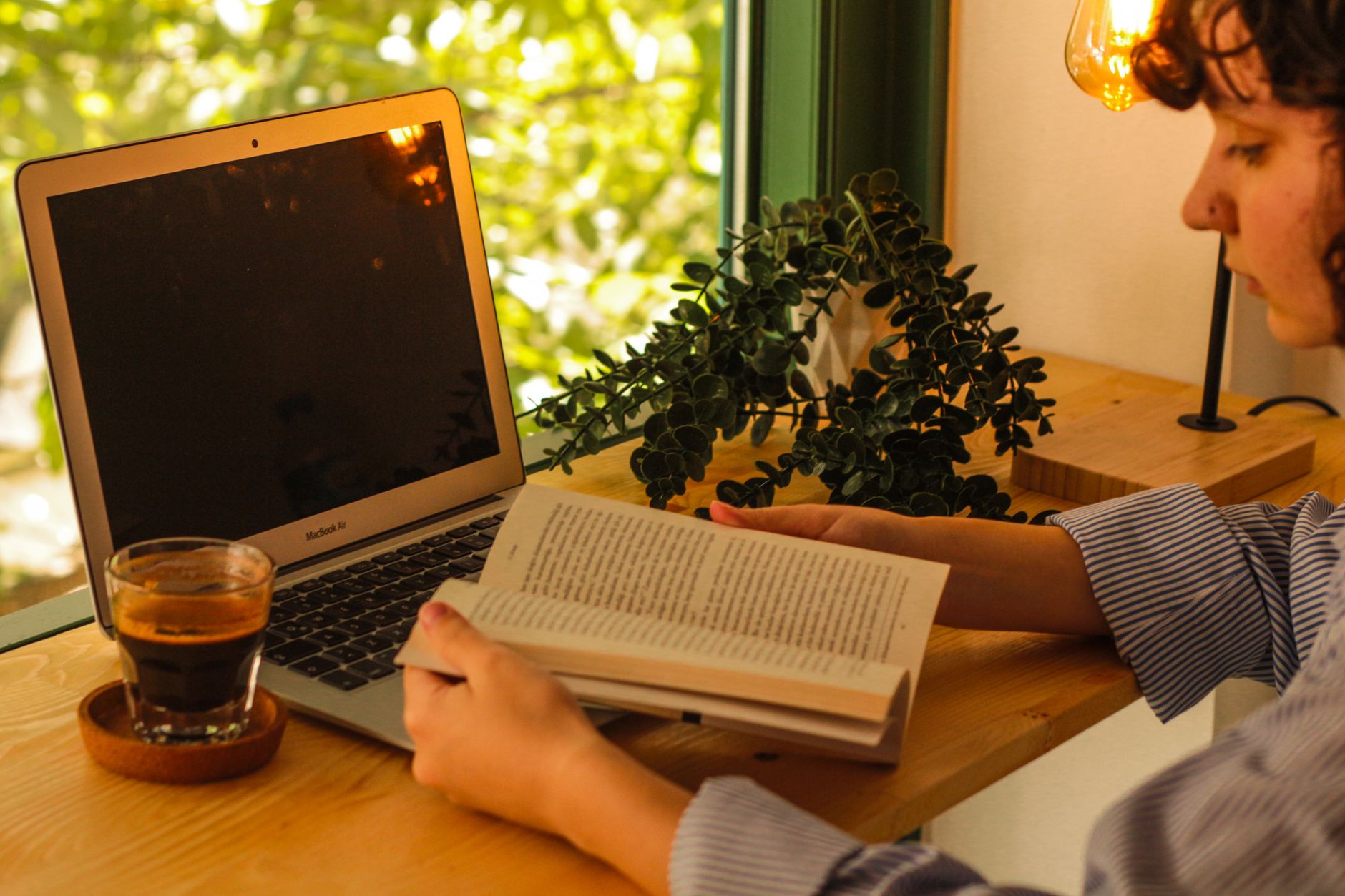 Espace de travail chaleureux avec un ordinateur portable, un café et un livre.